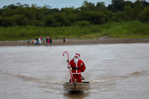 Relawan Jorge Alberto Barrozo, yang mengenakan kostum Sinterklas, berlayar dengan kano mengantarkan hadiah kepada anak-anak di komunitas tepi sungai di daerah pedesaan Careiro da Varzea, negara bagian Amazonas, Brasil, Sabtu (20/12/2025). Foto: Michael Dantas/AFP