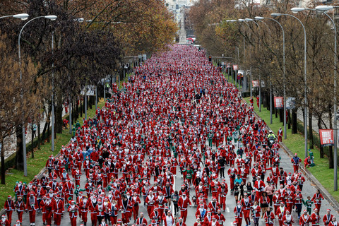 Orang-orang yang mengenakan kostum Sinterklas mengikuti perlombaan lari amal di Madrid, Spanyol, Minggu (21/12/2025). Foto: OSCAR DEL POZO / AFP