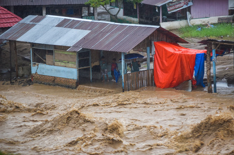 Warga berada di sebuah bangunan yang sudah terendam air di bantaran sungai Batang Air Dingin, Lubuk Minturun, Padang, Sumatera Barat, Selasa (30/12/2025). Foto: Iggoy el Fitra/ANTARA FOTO