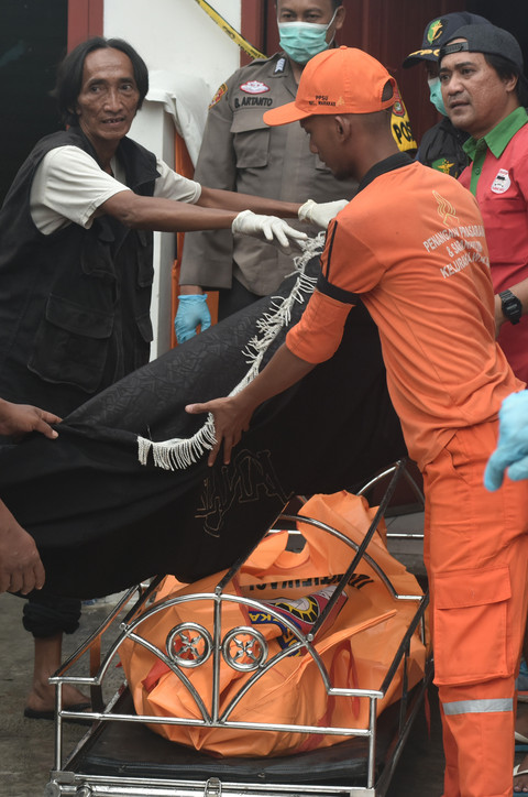Personel Kepplisian bersama relawan dan petugas Penanganan Prasarana dan Sarana Umum (PPSU) menutup dengan kain kantong berisi jenazah korban diduga keracunan di Warakas VIII, Jakarta Utara, Jumat (2/1/2026). Foto: Fakhri Hermansyah/ANTARA FOTO