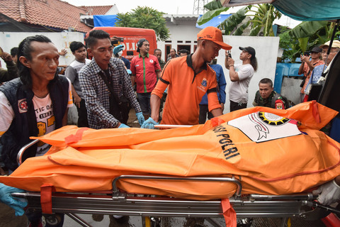 Relawan bersama petugas Penanganan Prasarana dan Sarana Umum (PPSU) memindahkan jenazah korban diduga keracunan ke mobil ambulance di Warakas VIII, Jakarta Utara, Jumat (2/1/2026). Foto: Fakhri Hermansyah/ANTARA FOTO