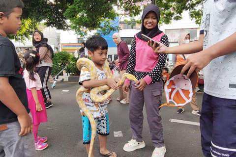 Seorang anak kecil berinteraksi dengan ular saat Car Free Day di Depok, Jawa Barat, Minggu (4/1/2026). Foto: kumparan