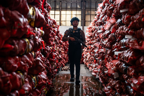 Polisi berjaga di samping barang bukti bawang bombai ilegal di Kompleks Pergudangan Bandarharjo, Semarang, Jawa Tengah, Sabtu (10/1/2026). Foto: Aprillio Akbar/ANTARA FOTO