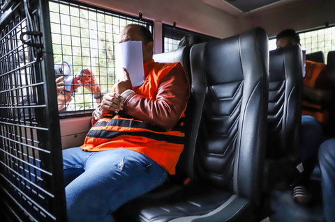 Staf PT Wanatiara Persada Edy Yulianto duduk dan menutupi mukanya sembari menggunakan rompi tahanan di dalam mobil tahanan usai menjalani pemeriksaan di Gedung Merah Putih KPK, Jakarta, Minggu (11/1/2026). Foto: Asprilla Dwi Adha/ANTARA FOTO