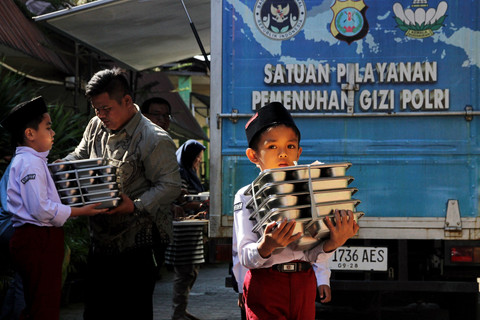 Siswa membawa tumpukan makan bergizi gratis di Sekolah Madrasah Ibtidaiyah Negeri Medan, Sumatera Utara, Rabu (14/1/2026). Foto: Yudi Manar/ANTARA FOTO 