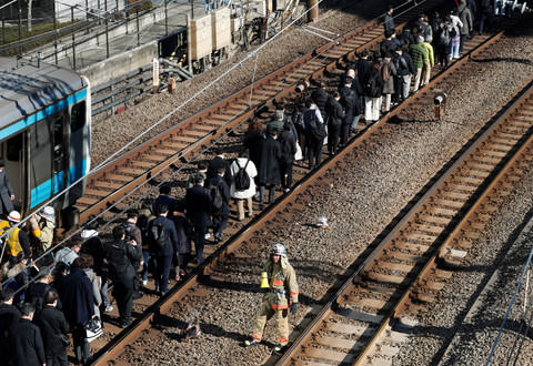 Penumpang yang dievakuasi dari kereta yang terhenti di jalur Keihin-Tohoku berjalan menuju stasiun Tamachi di Tokyo, Jepang, Jumat (16/1/2026). Foto: Kim Kyung-Hoon/REUTERS