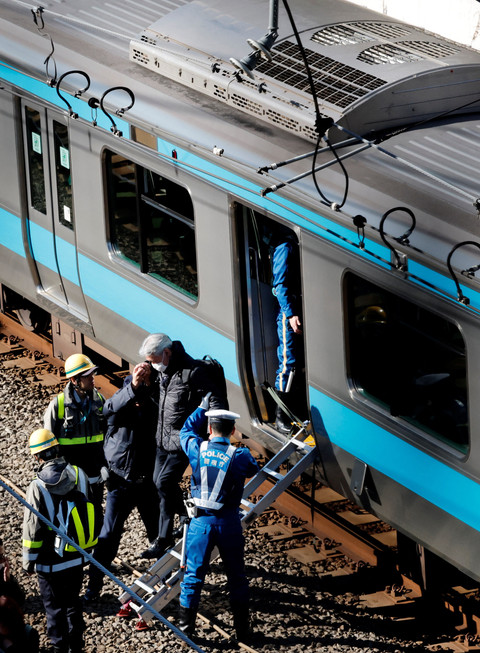 Para polisi membantu evakuasi penumpang dari kereta yang terhenti di jalur Keihin-Tohoku, dekat stasiun Tamachi di Tokyo, Jepang, Jumat (16/1/2026). Foto: Kim Kyung-Hoon/REUTERS