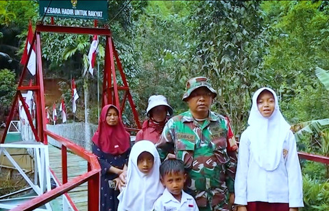 TNI dan warga berdiri di depan Jembatan Gantung Ciharuman yang baru dibangun di sekitar Sungai Ciharuman, Kabupaten Pangandaran, Jawa Barat. Foto: Dok. Bakom RI