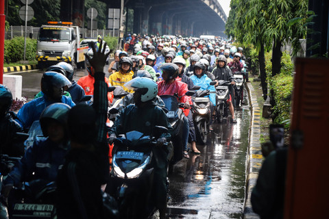 Petugas kepolisian mengatur lalin untuk para pengendara sepeda motor masuk ke Tol Cililitan 2 akibat banjir di kawasan Gerbang Tol Pulogebang, Jakarta, Minggu (18/1/2026). Foto: Iqbal Firdaus/kumparan