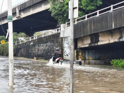 Pengendara sepeda motor melintasi banjir yang mencapai kedalaman 50 cm usai diguyur hujan di Jl. Ahmad Yani, Cempaka Putih, Jakarta Pusat, Minggu pagi (18/1/2026). Foto: Jeni Ritanti/kumparan