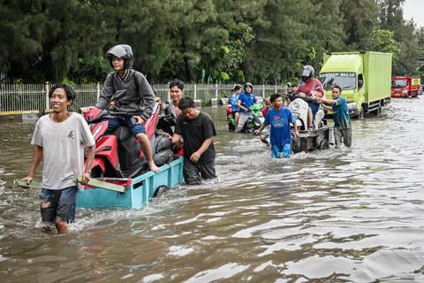 Pengendara sepeda motor menaiki gerobak untuk menerobos banjir di ruas Jalan Jembatan Tiga Raya, Penjaringan, Jakarta, Minggu (18/1/2026). Foto: Sulthony Hasanuddin/ANTARA FOTO 