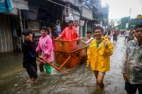 Warga berjalan sembari mendorong gerobak melintasi genangan air banjir di kawasan Gunung Sahari, Jakarta, Minggu (18/1/2026). Foto: Iqbal Firdaus/kumparan