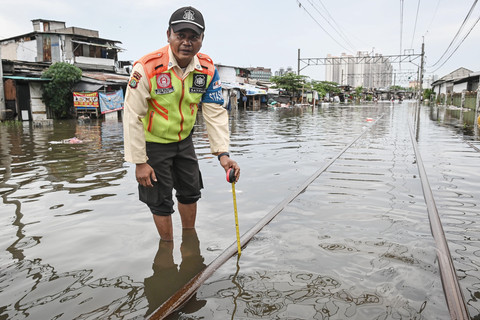Petugas mengukur ketinggian banjir yang merendam perlintasan kereta di kawasan Kampung Bandan, Jakarta, Minggu (18/1/2026). Foto: Sulthony Hasanuddin/ANTARA FOTO 
