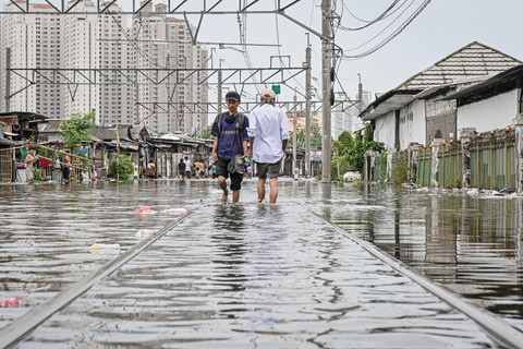 Warga melintasi perlintasan kereta yang terendam banjir di kawasan Kampung Bandan, Jakarta, Minggu (18/1/2026). Foto: Sulthony Hasanuddin/ANTARA FOTO 