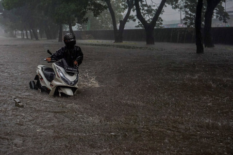 Seorang warga mendorong sepeda motornya di jalan yang terendam banjir di Jalan Daan Mogot, Jakarta, Kamis (22/1/2026). Foto: Ika Maryani/ANTARA FOTO