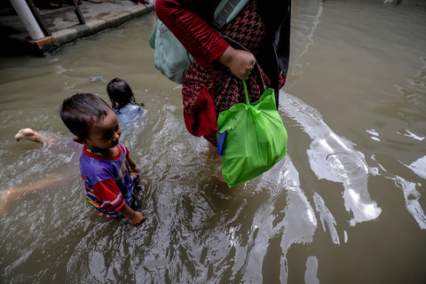 Warga melintasi banjir yang menggenangi Kampung Sungai Begog, Kelurahan Semper Timur, Kecamatan Cilincing, Jakarta Utara, Jumat (23/1/2026). Foto: Jamal Ramadhan/kumparan