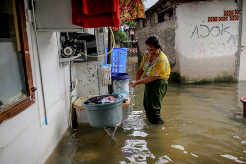 Warga mencuci pakaian di depan rumahnya saat banjir masih menggenangi permukiman warga RW 02, Kelurahan Rawa Buaya, Cengkareng, Jakarta Barat, Sabtu (24/1/2026). Foto: Jamal Ramadhan/kumparan