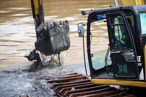 Petugas gabungan melakukan pengerukan sedimentasi lumpur di Kali Sepak menggunakan alat berat, Jakarta Barat, pada Senin (26/1/2026). Foto: Iqbal Firdaus/kumparan