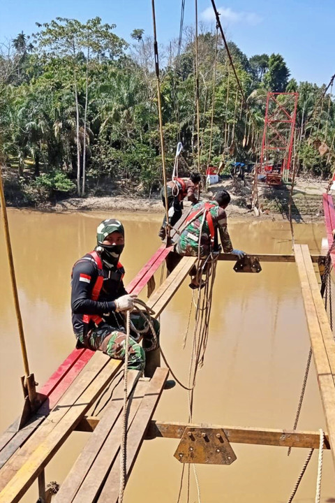 Petugas tengah melakukan penyelesaian akhir pembangunan jembatan dengan pengecetan dan pemasangan pelat lantai di Desa Kajeung, Kecamatan Sungai Mas, Kabupaten Aceh Barat. Foto: Dok. Bakom RI