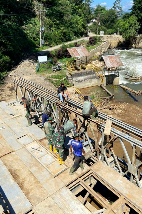 Petugas TNI tengah memasang papan lantai jembatan dan pengunci lantai agar menjadi permukaan jalan yang rata dan kokoh untuk jembatan bailey di PLTA Angkup, Aceh Tengah. Foto: Dok. Bakom RI