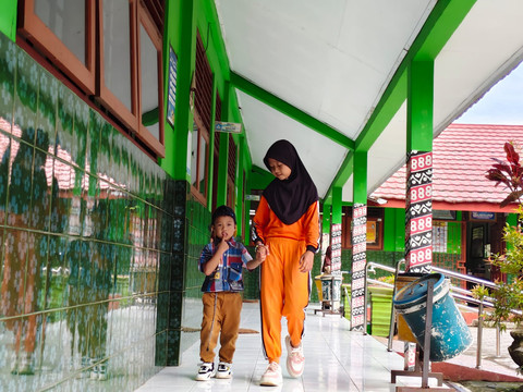 Ariendra Ralea Irgantari (9) membawa adiknya, Reyfan Elcaraka Fahturohman (4), ke sekolah di SD Negeri Gembongan, Kalurahan Salamrejo, Kapanewon Sentolo, Kabupaten Kulon Progo, Rabu (28/1). Foto: Widya Islamiati/kumparan