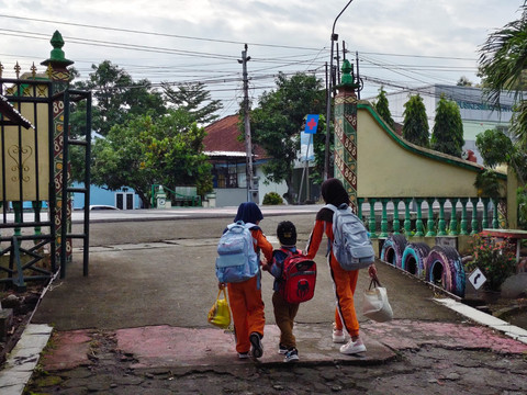 Ariendra Ralea Irgantari (9) membawa adiknya, Reyfan Elcaraka Fahturohman (4), ke sekolah di SD Negeri Gembongan, Kalurahan Salamrejo, Kapanewon Sentolo, Kabupaten Kulon Progo, Rabu (28/1). Foto: Widya Islamiati/kumparan