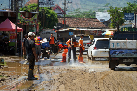 Personel BPBD Tulungagung menyemprotkan air saat membersihkan endapan lumpur dari atas aspal Jalan Raya Popoh, Tulungagung, Jawa Timur, Sabtu (31/1/2026). Foto: Destyan Sujarwoko/ANTARA FOTO