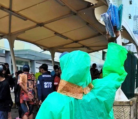 Adi (39), pedagang jas hujan keliling, menawarkan barang dagangannya di sekitar kawasan Bundaran HI, Jakarta Pusat, Minggu (1/2/2026). Foto: Jeni Ritanti/kumparan