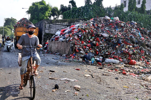 Warga mengendarai sepeda melintas di dekat tumpukan sampah di Kota Depok, Jawa Barat, Kamis (5/2/2026). Foto: Yulius Satria Wijaya/ANTARA FOTO