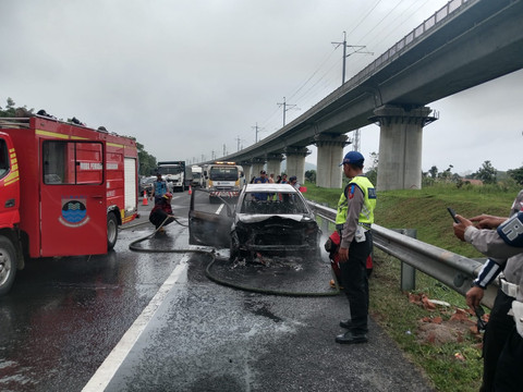 Sebuah mobil Honda Mobilio berwarna putih terbakar saat melintas di ruas Jalan Tol Purbaleunyi KM 127 jalur A, Senin (9/2/2026). Foto: Dok. Polres Cimahi 