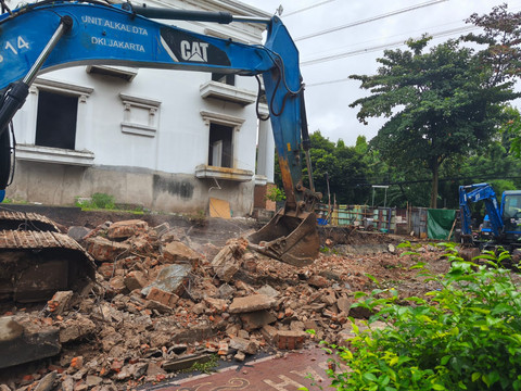 Gunakan alat berat, petugas bersihkan area yang terdampak dari robohnya bangunan tembok rumah di sebelah SMP Negeri 182 Jakarta, Kalibata Jakarta Selatan, Senin (16/2/2026). Foto: Jeni Ritanti/kumparan