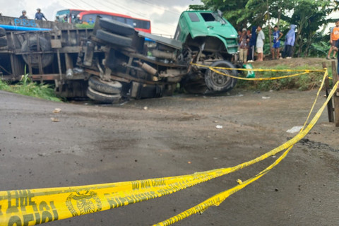 Truk kontainer yang terguling di akses jalan irigasi Desa Kondangjaya, Kecamatan Karawang Timur, Karawang, Senin (16/2/2026). Foto: kumparan