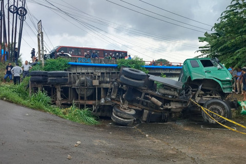 Truk kontainer yang terguling di akses jalan irigasi Desa Kondangjaya, Kecamatan Karawang Timur, Karawang, Senin (16/2/2026). Foto: kumparan
