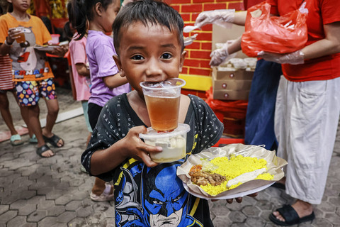 Seorang anak menggigit gelas plastik usai mengambil makanan berbuka puasa di Wihara Dharma Bakti, Jakarta, Senin (23/2/2026). Foto: Dhemas Reviyanto/ANTARA FOTO