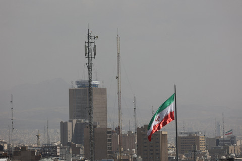 Bendera Iran berkibar saat Israel dan AS melancarkan serangan terhadap Iran, di Teheran, Iran, Sabtu (28/2/2026). Foto: Majid Asgaripour/WANA via Reuters