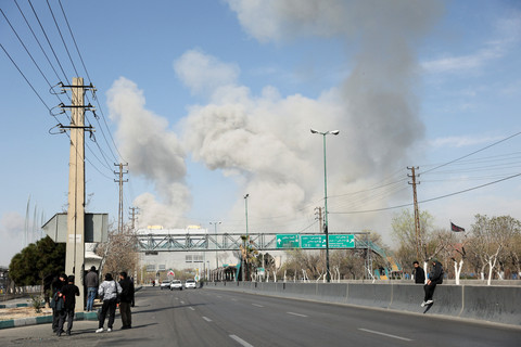 Orang-orang berkumpul di pinggir jalan sementara asap mengepul di latar belakang setelah ledakan, di tengah konflik AS-Israel dengan Iran, di Teheran, Iran, Kamis (5/3/2026). Foto: Majid Asgaripour/WANA via Reuters