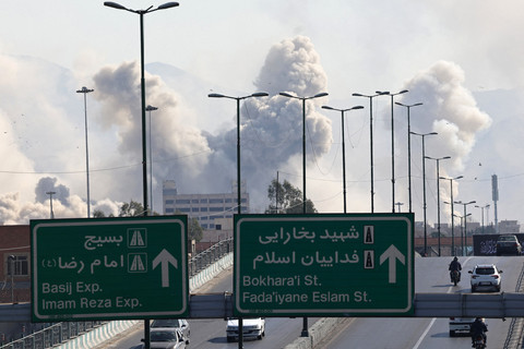 Kendaraan-kendaraan melaju di jalan raya dengan latar belakang asap yang mengepul setelah serangan terhadap ibu kota Iran, Teheran, Kamis (5/3/2026). Foto: Atta Kenare/AFP