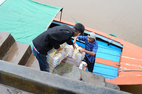 Tim Satuan Pelayanan Pemenuhan Gizi (SPPG) Gandus memasukkan menu MBG ke dalam perahu sebelum diantarkan ke anak-anak sekolah di Wilayah Gandus, Palembang. Foto: Dok. Bakom RI