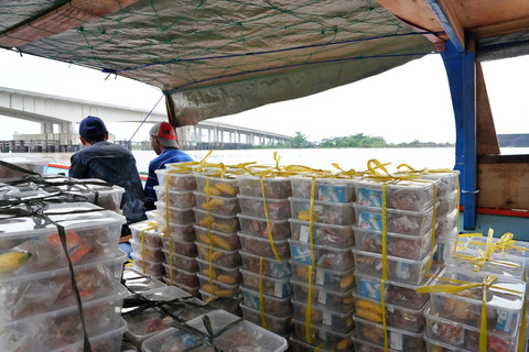 Menu makanan MBG berada dalam perahu yang akan berangkat menyusuri arus Sungai Musi di Wilayah Gandus, Palembang. Foto: Dok. Bakom RI