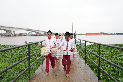 Anak-anak menerima menu MBG setelah Tim Satuan Pelayanan Pemenuhan Gizi (SPPG) Gandus mengantarkannya melalui Sungai Musi di Wilayah Gandus, Palembang. Foto: Dok. Bakom RI