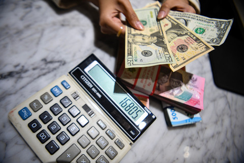 Petugas menunjukkan pecahan mata uang dolar Amerika Serikat dan mata uang Rupiah di Kantor Cabang BNI Pasar Baru, Jakarta, Selasa (10/3/2026). Foto: Muhammad Adimaja/ANTARA FOTO
