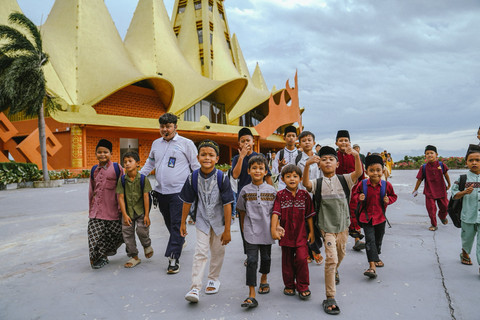 Anak-anak menerima paket perlengkapan sekolah dari ASDP dalam memperingati satu tahun Danantara di Masjid BSI, kawasan Bakauheni Harbour City, Lampung Selatan. Foto: Dok. ASDP