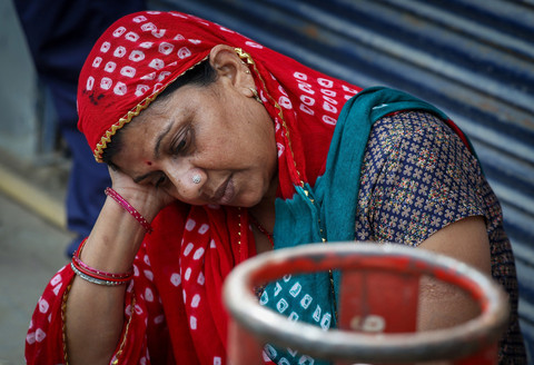 Seorang wanita duduk di samping tabung LPG kosong sambil menunggu di luar sebuah agen gas di tengah gangguan pasokan menyusul konflik AS-Israel dengan Iran, di Noida, India, 12 Maret 2026. Foto: REUTERS/Bhawika Chhabra