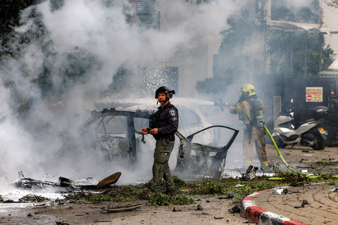 Petugas pemadam kebakaran memadamkan api di dalam kendaraan setelah terkena dampak proyektil dari serangan Iran di Tel Aviv, Minggu (15/3/2026). Foto: JACK GUEZ / AFP