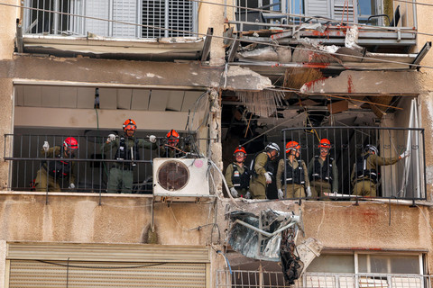 Pasukan keamanan Israel dan petugas tanggap darurat memeriksa sebuah bangunan yang terkena serangan proyektil Iran di lingkungan perumahan di Bnei-Brak, Tel Aviv, Minggu (15/3/2026). Foto: JACK GUEZ / AFP