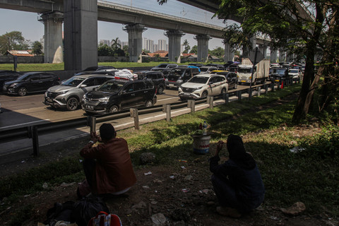 Dua warga menyaksikan kendaraan pemudik yang terjebak kemacetan di Jalan Tol Jakarta-Cikampek, Cikarang, Kabupaten Bekasi, Jawa Barat, Kamis (19/3/2026). Foto: Darryl Ramadhan/ANTARA FOTO