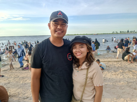 Maria (30) bersama suaminya saat berlibur untuk menyenangkan anaknya di Pantai Ancol pada Minggu (22/3). Foto: Ryan Iqbal/kumparan