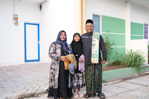 Warsana bersama istri dan anaknya di depan rumah baru mereka di Kampung Nelayan Sejahtera, Desa Eretan Kulon, Kabupaten Indramayu. Usai salat Idulfitri di masjid setempat, Sabtu (21/3/2026) mereka merayakan lebaran pertama dengan rasa tenang.   Foto: Dok. Biro Humas Kemensos / Adhytia D. Lesmana