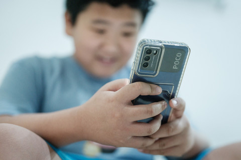 Ilustrasi - Anak Anak Bermain Handphone Foto: Yasuyoshi Chiba/AFP