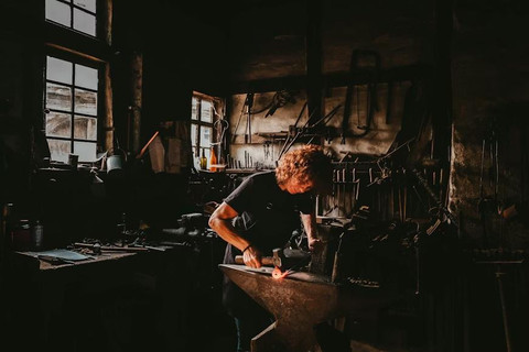 Aktivitas seorang pengrajin besi tradisional yang sedang menempa logam panas di atas paron. (unsplash.com/@fve_photo)
